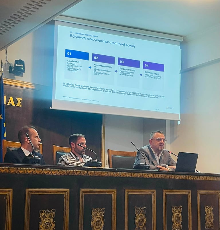 Τρεις άνδρες σε πάνελ με slide παρουσίασης σε επίσημο συνεδριακό χώρο